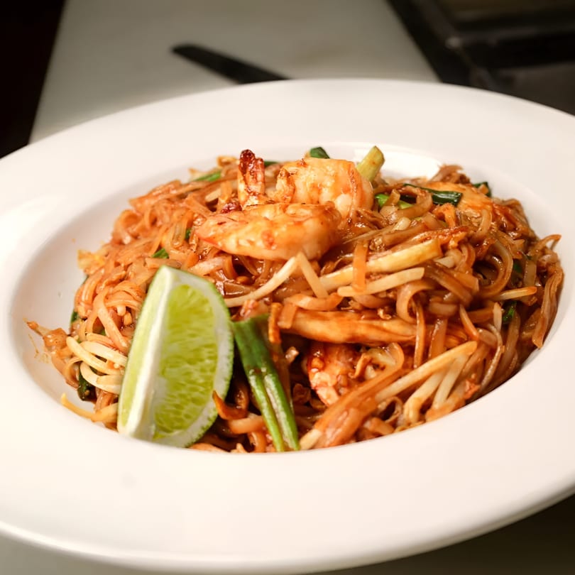 Royal Thai and Sushi's Pad Thai with shrimp, noodles, bean sprouts, and a lime wedge.
