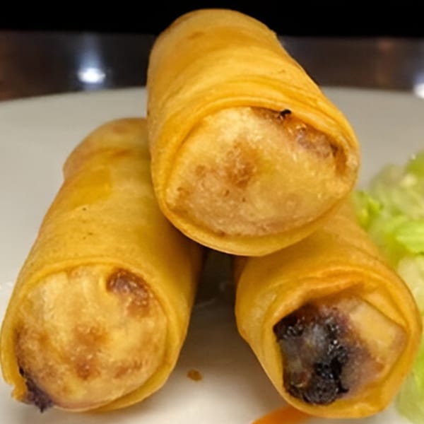 Three crispy golden Thai spring rolls with lettuce on a white plate.